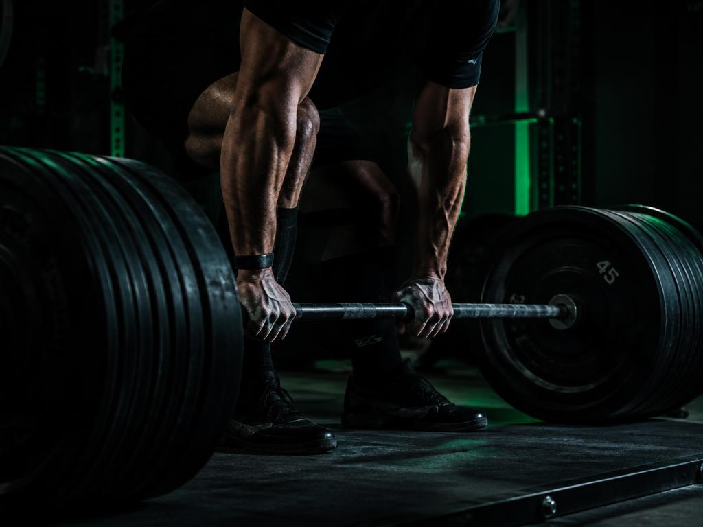 Athlete gripping a heavily loaded barbell on a lifting platform